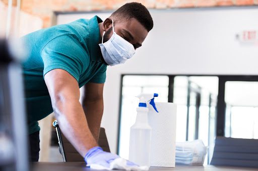 Professional cleaner wipes down pathogens in the workplace off an office desk