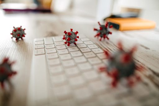 Close up model of corona virus on desk and keyboard in office to demonstrate omicron variant disinfecting