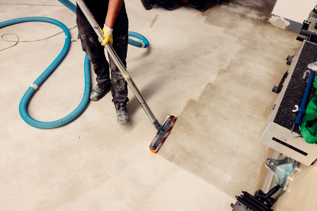 Construction worker vacuuming a concrete floor to prepare it for the application of an epoxy coating